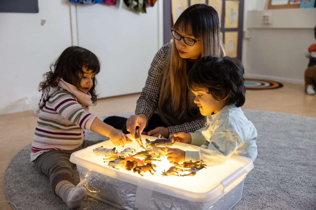 Pedagog och barn utforskar vid ett ljusbord