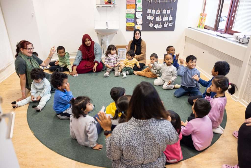 Barn och pedagoger i samling på golvet
